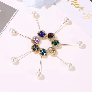 Macro detail of 7 crystal brooch pins with pearls and rhinestones on pink background