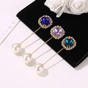 Three elegant crystal stick pins with pearls and rhinestones on black velvet cushion