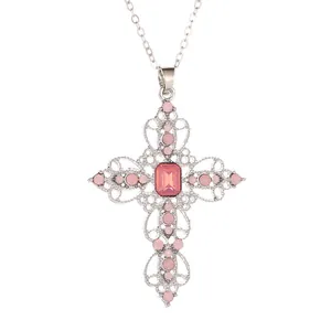 Collier croix argenté avec motif floral creux et gemmes roses sur fond blanc