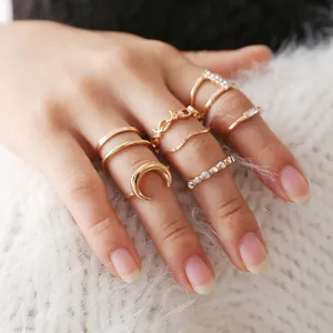 Close-up of bohemian gold moon and diamond rings set on soft white knit background