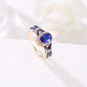 Classic gold ring with oval blue zircon and pavé diamonds on a minimalist white background