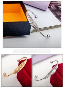 Dettaglio macro di bracciali aperti a foglia con texture piumata in oro e argento