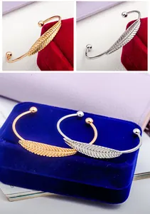 Dettagli dei bracciali aperti a foglia in oro e argento su astuccio in velluto