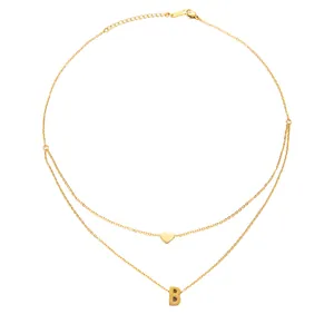 Macro detail of gold double-layered necklace featuring heart and letter B pendants