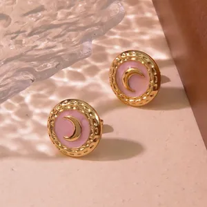Close-up of pink enamel moon stud earring with vintage gold hammered metal texture