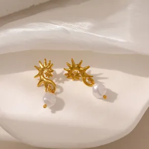 Dettaglio di orecchini a sole dorati con perle bianche eleganti su sfondo di seta bianca