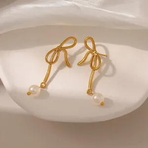 Dettaglio ravvicinato di orecchini a fiocco dorato con eleganti perle bianche