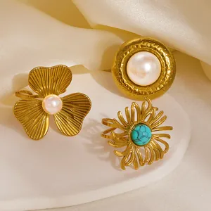 Set de anillos florales dorados con perlas y turquesa sobre tela de seda fina