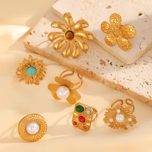 Detailed set of 18k gold plated floral rings with pearls and turquoise on a stone background