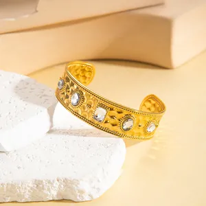 Dettaglio del bracciale aperto in oro 18k con texture martellata e cinque gemme chiare