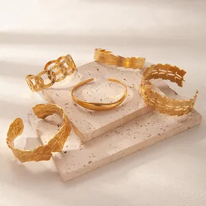Detailed collection of five vintage 18K gold plated stainless steel bangles on stone