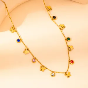 Detail of gold butterfly necklace with multicolor cubic zirconia charms on beige display