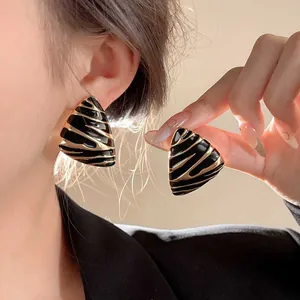 Mannequin portant des boucles d'oreilles triangles vintage avec émail noir et rayures dorées