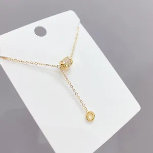 Dettaglio collana dorata con pendente a cilindro micro-pave e ciondolo rotondo pendente