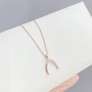 Dettaglio della collana Wishbone in oro rosa con zirconi su supporto in pelle bianca