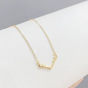 Minimalist golden elk antler pendant necklace on a premium white leather display