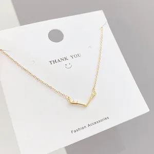 Detailed close-up of a golden elk antler pendant necklace on a white display card