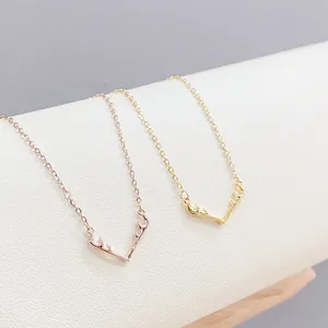 Elegant gold and rose gold elk antler pendant necklaces on a minimalist display stand