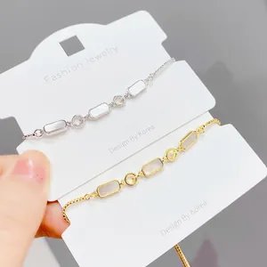 Détail de bracelets coquillages réglables en or et argent sur carte à bijoux