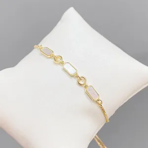 Bracelet ajustable en or et nacre avec maillons rectangulaires sur un coussin blanc