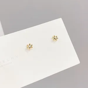 Three-piece set of elegant gold flower stud earrings with zircon centers on white card