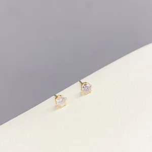 Detail of minimalist six-prong stud earrings with round cubic zirconia in golden setting