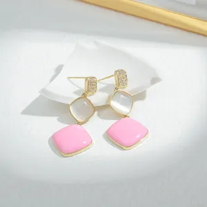 Detailed view of S925 silver needle drop earrings with cat eye stones and pink enamel