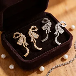 Orecchini a fiocco oro e argento con strass scintillanti in una scatola regalo di velluto
