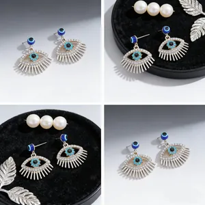 Macrodetails van evil eye kwastjes oorbellen met blauwe kristallen en zilveren finish
