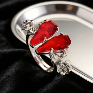 Detailed close-up of gothic open ring with red coffin stones and floral silver carvings