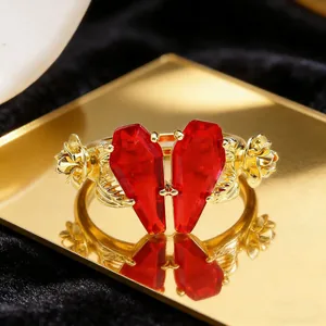 Macro detail of gothic gold coffin heart ring with red stones and roses on mirror