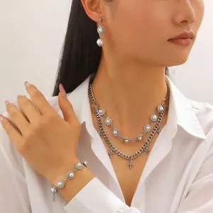 Dettaglio della collana in argento con croce e set di gioielli con perle indossati da modella