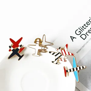 Five assorted colorful airplane enamel pins made of metal alloy on a white plate