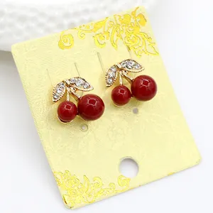 Macro view of cherry stud earrings with red globes and sparkling crystal leaves