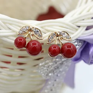 Macro view of cute cherry earrings featuring red globes and sparkling rhinestone leaves