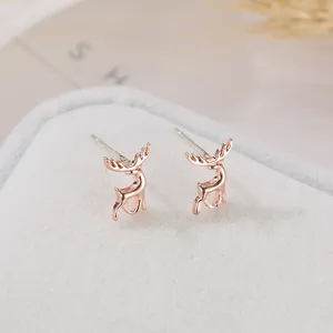 Dettaglio macro di orecchini a lobo a forma di renna oro rosa su portagioie grigio