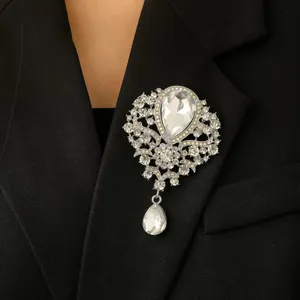 Elegant silver teardrop crown brooch with shimmering crystals on a black suit jacket