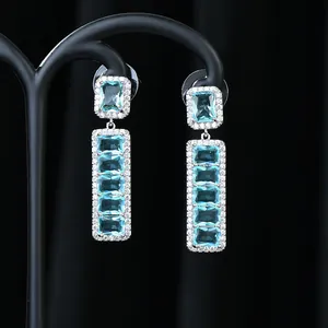 Dettaglio di orecchini pendenti in argento con pietre blu rettangolari e pavé di cristalli