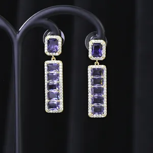 Dettaglio ravvicinato di orecchini pendenti vintage in oro con cristalli viola rettangolari