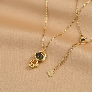 Collier astronaute plaqué or avec pierre œil de chat sur fond en soie de couleur champagne