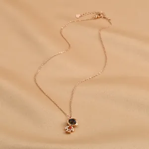 Gros plan détaillé du collier astronaute en or rose sur un élégant tissu en soie champagne