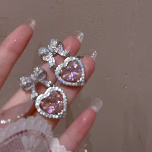 Dettaglio dell'orecchino a cuore rosa con fiocco a farfalla e micro-set di zirconi
