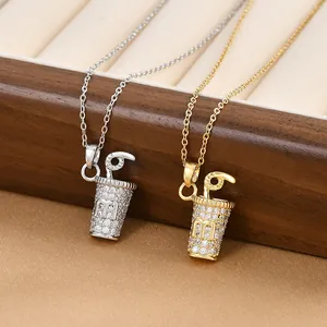 Macro shot of gold and silver drink cup pendants with m letter and white zircons