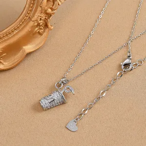 Close-up of a silver coffee cup pendant with white crystals and a heart-shaped charm