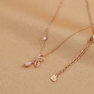 Detailed macro view of gold-plated necklace with bow pendant and pink drop stone