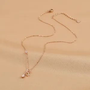 Close-up of rose gold bow necklace with zircon inlay and pear-shaped opal stone