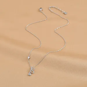 Macro shot of S925 silver bow necklace with opal teardrop and heart pendant on fabric