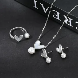 Elegante set di collana orecchini e anello a cuore con perle su sfondo scuro
