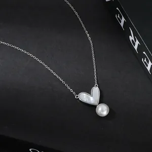 Dettaglio della collana a cuore in argento con madreperla e perla rotonda su sfondo nero