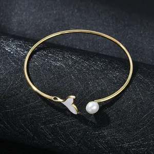 Elegant gold-tone open cuff bracelet with seashell fish tail and white pearl accent